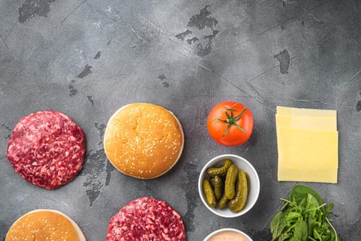 Ingredients for cooking burgers. Raw ground beef meat cutlets set, on gray stone background, top view flat lay, with copy space for text