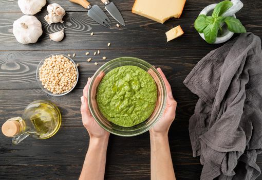 Step by step cooking italian pesto sauce. Step 8 - mixing all ingredients. Pesto sauce is ready. Fresh green basil, parmesan cheese, nuts, olive oil and garlic top view on black wooden table