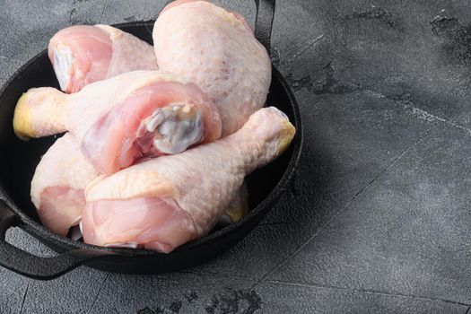 Raw organic chicken legs set, in frying cast iron pan, on gray stone background, with copy space for text