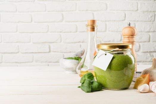 Italian cuisine. Preparing homemade italian pesto sauce. Homemade pesto sause in a glass jar with a blank tag, mock up design