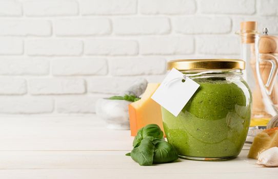 Italian cuisine. Preparing homemade italian pesto sauce. Homemade pesto sause in a glass jar with a blank tag, mock up design