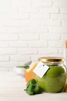 Italian cuisine. Preparing homemade italian pesto sauce. Homemade pesto sause in a glass jar with a blank tag, mock up design