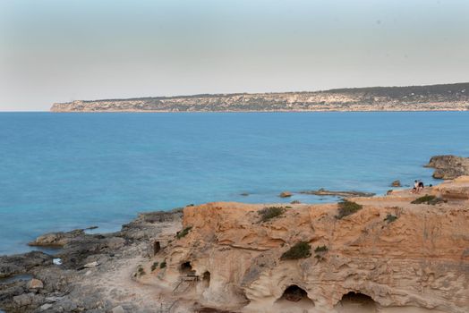 Young man in the cave of Beautiful Cala d en Baster on the island of Formentera in the Balearic Islands in Spain.