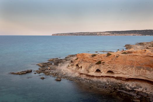 Young man in the cave of Beautiful Cala d en Baster on the island of Formentera in the Balearic Islands in Spain.