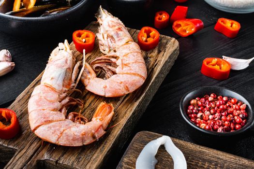 Tiger shrimps on cutting board over black wooden table, food photo.