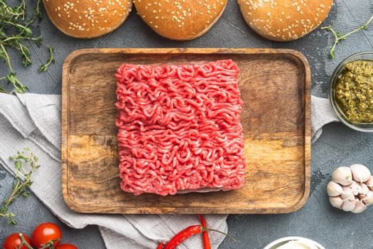 Fresh raw minced beef steak burgers with spices ingredients set, on wooden tray, on gray stone background, top view flat lay