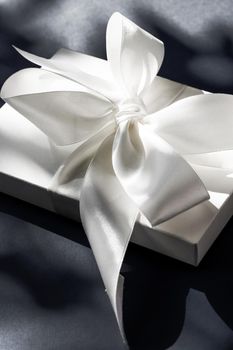 Anniversary celebration, shop sale promotion and luxe surprise concept - Luxury holiday white gift box with silk ribbon and bow on black background, luxe wedding or birthday present