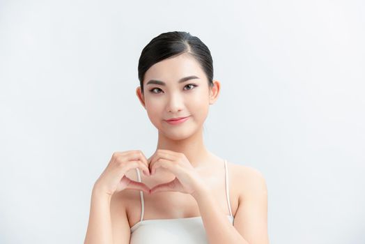 Portrait of woman showing heart figure sign with hands near chest isolated