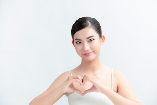 Portrait of woman showing heart figure sign with hands near chest isolated