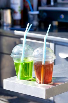 Street vendor of various drinks poured into transparent plastic cups. Vertical shot