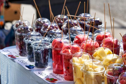 Street vendor of various fruits cut into transparent plastic cups. Close up