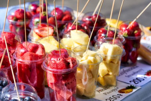 Street vendor of various fruits cut into transparent plastic cups. Close up