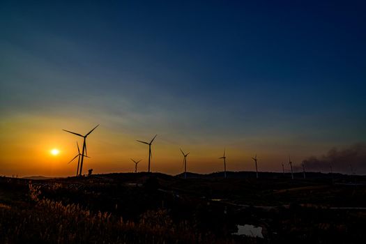 Wind turbine farm over sunset sky Generating Electricity. Renewable Power Supply