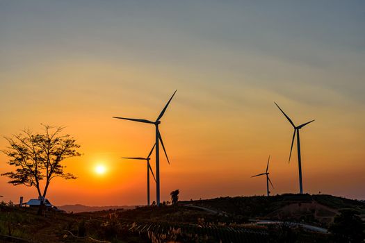 Wind turbine farm over sunset sky Generating Electricity. Renewable Power Supply