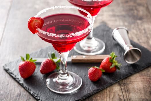 Strawberry margarita cocktail in glass on wooden table.