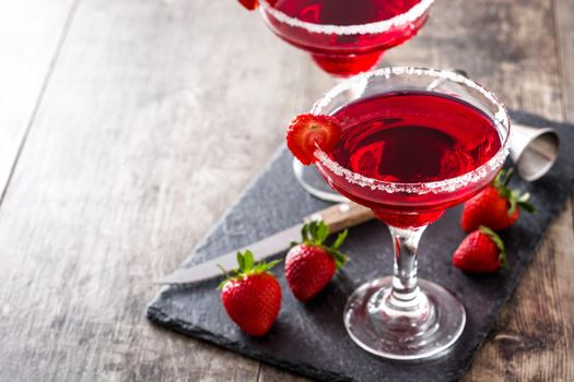 Strawberry margarita cocktail in glass on wooden table.