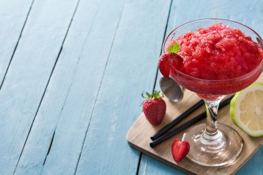 Strawberry margarita cocktail in glass on blue wooden table