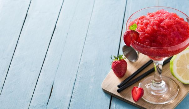 Strawberry margarita cocktail in glass on blue wooden table