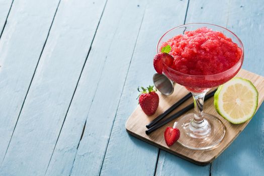 Strawberry margarita cocktail in glass on blue wooden table