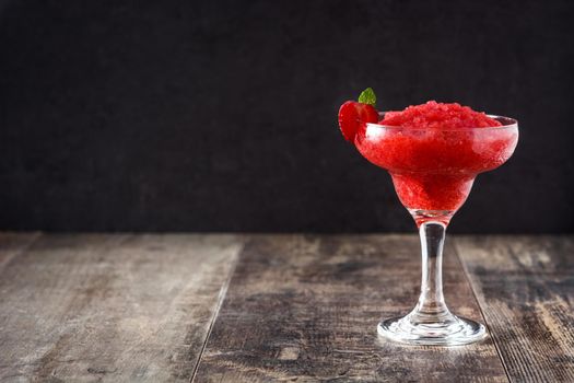 Strawberry margarita cocktail in glass on wooden table.