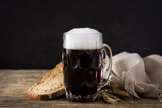 Traditional kvass beer mug with rye bread on wooden table