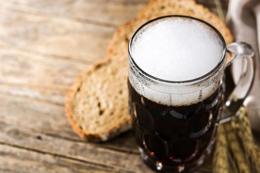 Traditional kvass beer mug with rye bread on wooden table