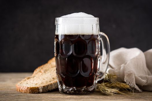 Traditional kvass beer mug with rye bread on wooden table