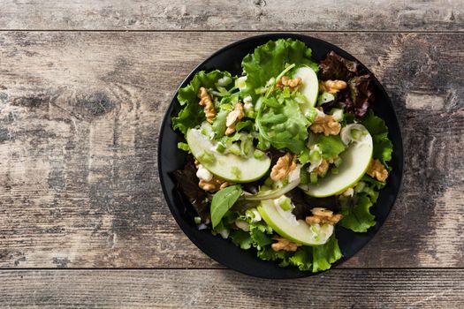 Fresh Waldorf salad with lettuce, green apples, walnuts and celery on wooden table