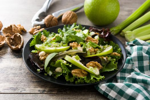 Fresh Waldorf salad with lettuce, green apples, walnuts and celery on wooden table