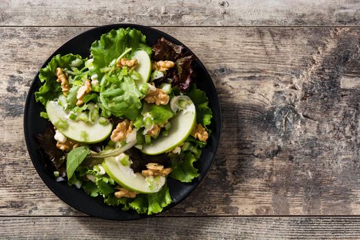 Fresh Waldorf salad with lettuce, green apples, walnuts and celery on wooden table