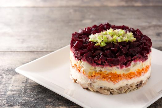 Traditional Russian herring salad with beetroot and carrots on wooden table