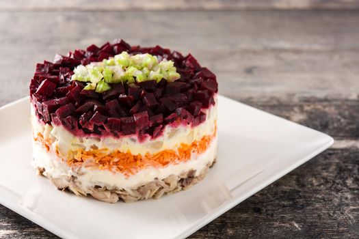 Traditional Russian herring salad with beetroot and carrots on wooden table