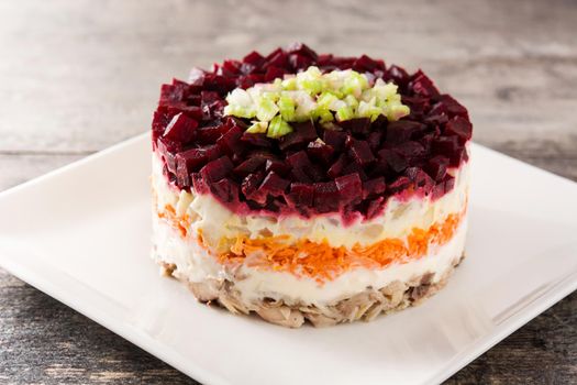 Traditional Russian herring salad with beetroot and carrots on wooden table