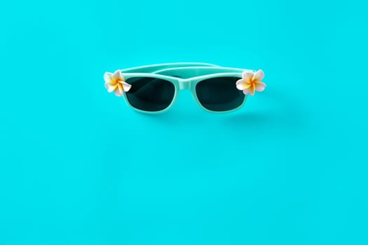 Sunglasses with flowers on turquoise background