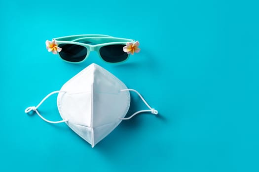 Sunglasses and protective face mask on blue background