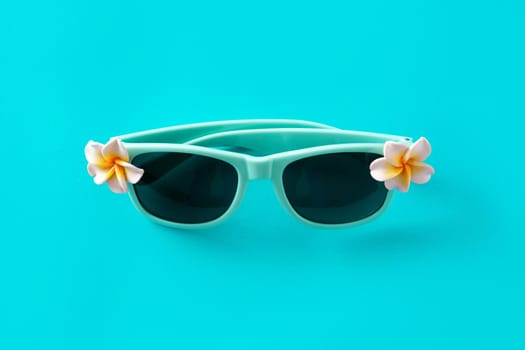 Sunglasses with flowers on turquoise background
