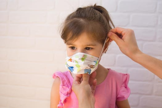 Mother putting protective mask pm her daughter. Coronavirus concept.