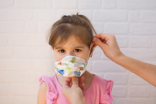 Mother putting protective mask pm her daughter. Coronavirus concept.