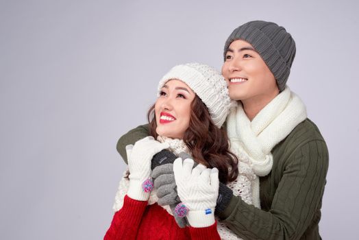 Happy young lovers in knitted woolen clothing hugging and looking together.