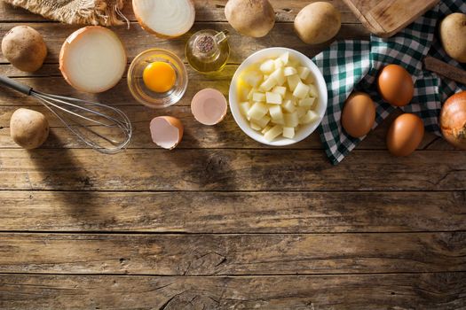 Spanish omelette tortilla ingredients: eggs, potatoes and onion on wooden background. Top view copy space
