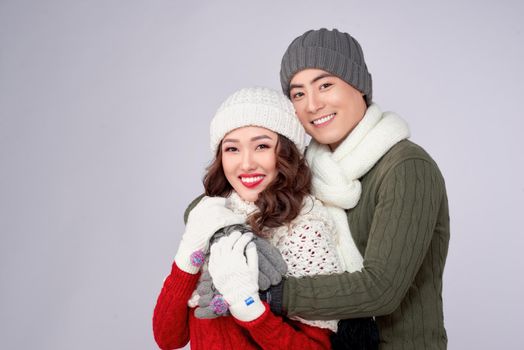 Happy young lovers in knitted woolen clothing hugging and looking together.