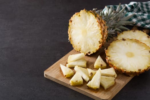 Fresh pineapple slices on black slate background