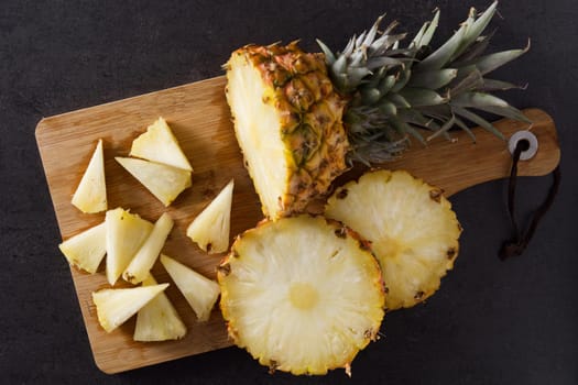 Fresh pineapple slices on black slate background