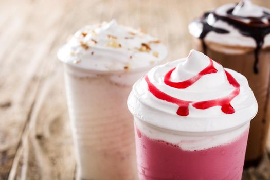 Strawberry, chocolate and white milkshakes on wooden table
