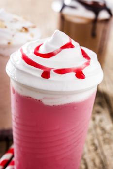 Strawberry, chocolate and white milkshakes on wooden table