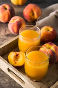 Natural peach juice in glass on wooden table