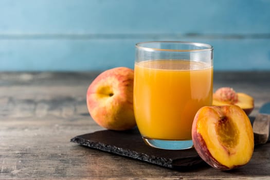 Natural peach juice in glass on wooden table