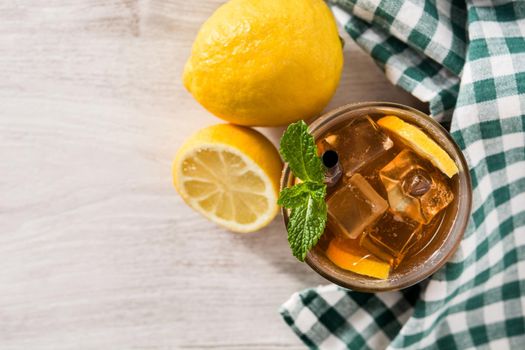 Iced tea drink with lemon in glass and ice on white wooden table