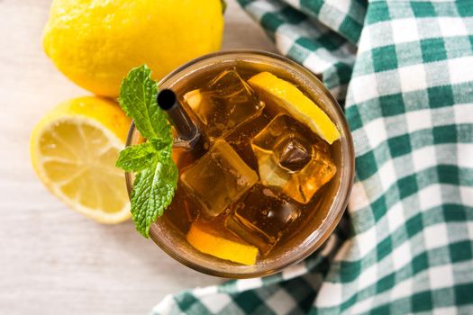 Iced tea drink with lemon in glass and ice on white wooden table