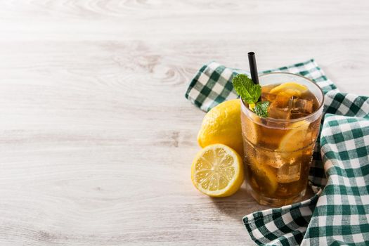 Iced tea drink with lemon in glass and ice on white wooden table